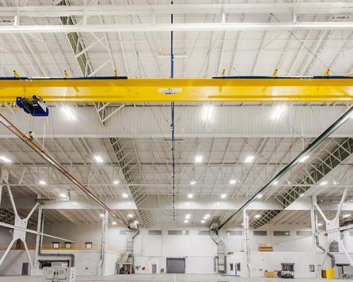 Interior of Lufthansa Technik Heavy Maintenance Facility. Large open space with white walls, bright lighting and yellow ceiling beams.